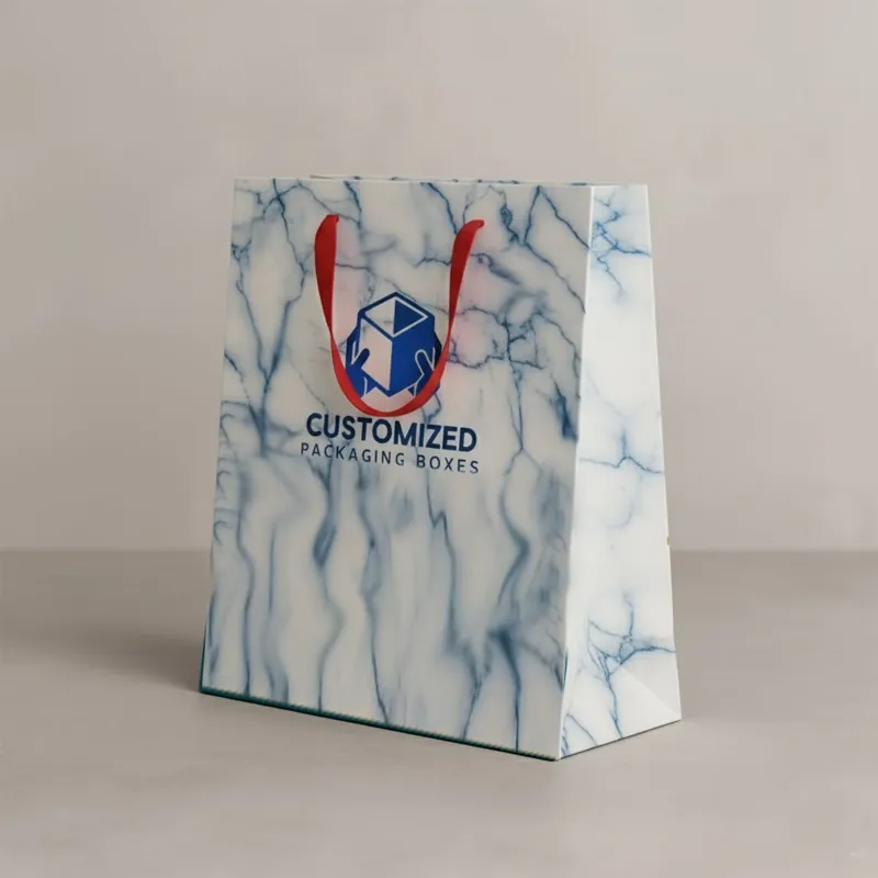 A branded gift bag with a white handle and a design on its surface rests on a neutral background.
